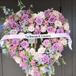 Heart-shaped floral wreath of pink and purple roses with a ribbon banner