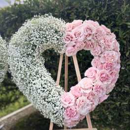 Heart-shaped floral display with pink roses and white baby's breath on an easel