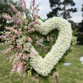 Heart-shaped floral wreath with white and pink flowers on an easel