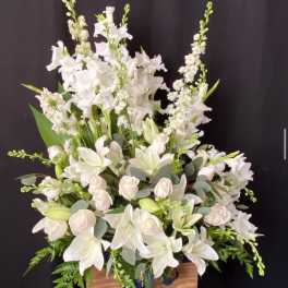White floral arrangement in a wooden stand with a blue ribbon