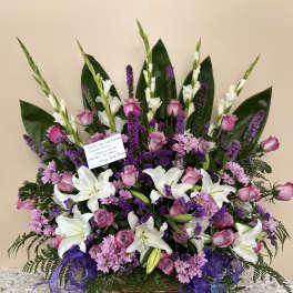 Basket arrangement of white lilies, pink roses, and purple flowers