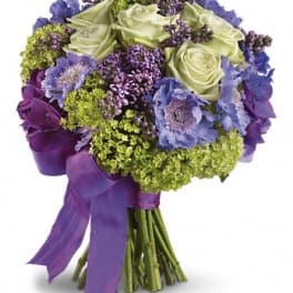 Purple and green bouquet with roses and blue flowers tied with a purple ribbon