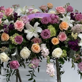 Large casket spray with roses, lilies, and purple flowers