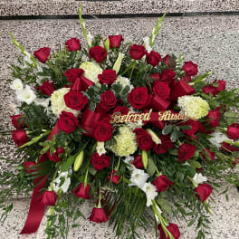 Large red and white floral funeral spray with ribbon and "Beloved Husband" sign