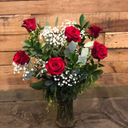 Red roses arranged in a clear glass vase with white baby's breath