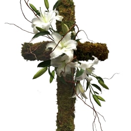 White lilies arranged on a moss-covered cross