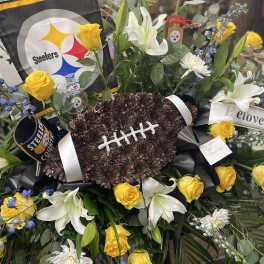 Football-shaped floral tribute with yellow roses and white lilies