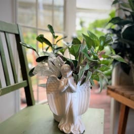Potted green houseplant in a white angel-shaped ceramic planter