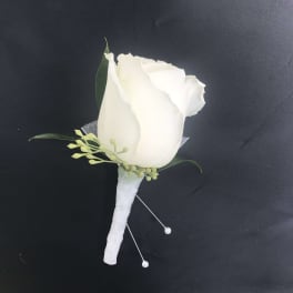 White rose boutonniere with small green accents on a wrapped stem