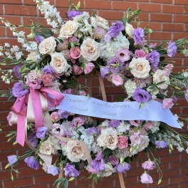 Large pastel floral wreath on an easel with pink and lavender ribbon