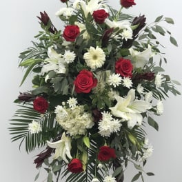 Standing floral spray with red roses, white lilies, and white daisies