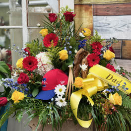 Floral arrangement with red and yellow roses, gerbera daisies, and a yellow ribbon