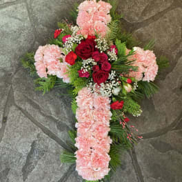 Cross-shaped floral arrangement with pink carnations and red roses