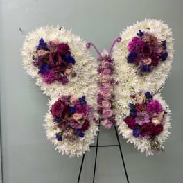 Butterfly-shaped floral arrangement with white and purple flowers on a stand