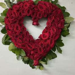 Heart-shaped arrangement of red roses with green foliage