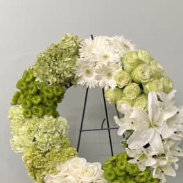 Circular floral wreath with white and green flowers on a black stand