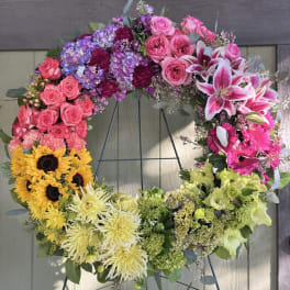 Colorful floral wreath on a stand with roses, lilies, sunflowers, and chrysanthemums