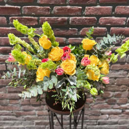 Yellow and pink rose arrangement in a dark vase