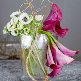 White anemones and magenta calla lilies in a glass vase