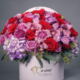 Large bouquet of red, pink, and purple flowers in a white box