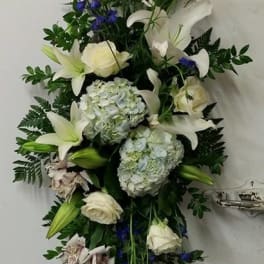 Tall floral spray with white lilies, roses, blue delphinium, and hydrangeas