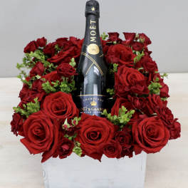 Red roses arranged around a Moët & Chandon champagne bottle in a white box