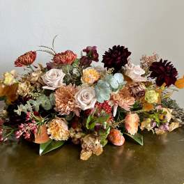 Low floral arrangement with roses, chrysanthemums, and dark dahlias
