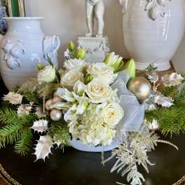 White roses and lilies arranged with holiday ornaments and ribbon