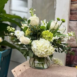 White and green floral arrangement in a glass vase