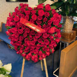 Large heart-shaped arrangement of red roses on an easel with a ribbon