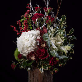 Red roses, white hydrangea, and orchids in a rustic wood vase