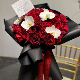 Bouquet of red roses with white orchids wrapped in black paper