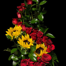 Tall arrangement of red roses and yellow sunflowers in a vase