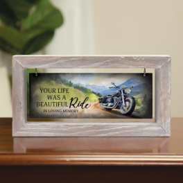 Memorial plaque in a light wood frame with a motorcycle scene