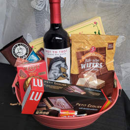 Gift basket with wine and assorted chocolates in a pink container
