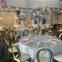 Tall pastel floral centerpieces on banquet tables in a decorated event hall