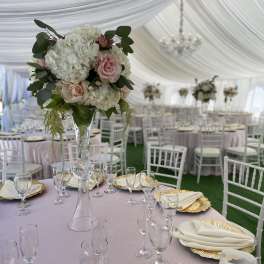 Tall floral centerpiece with white hydrangeas and pale pink roses in a clear vase