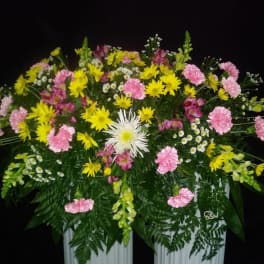 Large floral arrangement with pink and yellow flowers in a white container