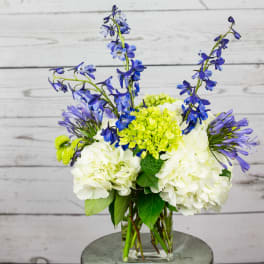 Blue and white flowers arranged in a clear glass vase