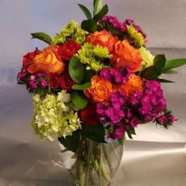 Colorful bouquet of roses and clustered blooms in a clear glass vase