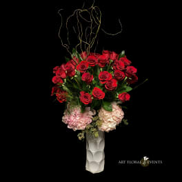 Red roses and pink hydrangeas in a tall white vase