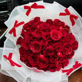 Bouquet of red roses wrapped in white paper with red bows