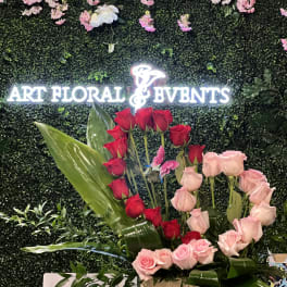 Red and pink roses arranged in a wooden box with large tropical leaves
