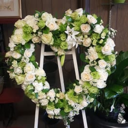 Heart-shaped floral wreath with white and green roses on a stand