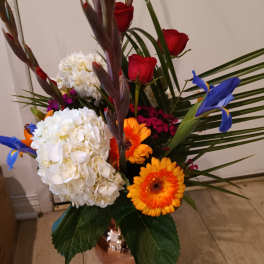 Mixed bouquet with red roses, white hydrangeas, and orange gerbera daisies in a vase