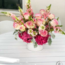Pink and cream roses with tall snapdragons in a white vase