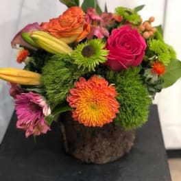 Colorful mixed bouquet with roses, lilies, and chrysanthemums in a rustic container