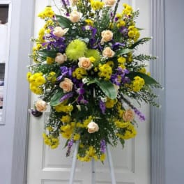 Tall standing floral spray with yellow and purple flowers on an easel