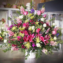 Large mixed bouquet in a white container with pink, white, and purple flowers