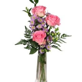 Pink roses and purple daisies in a tall glass vase